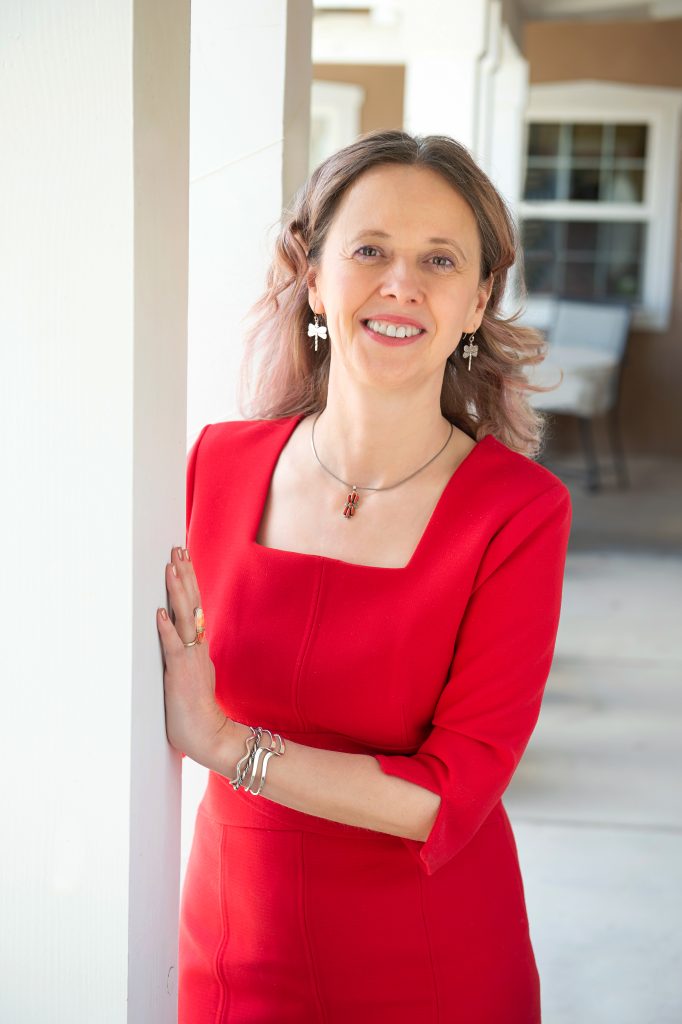 Mihaela standing outside, smiling in a red dress