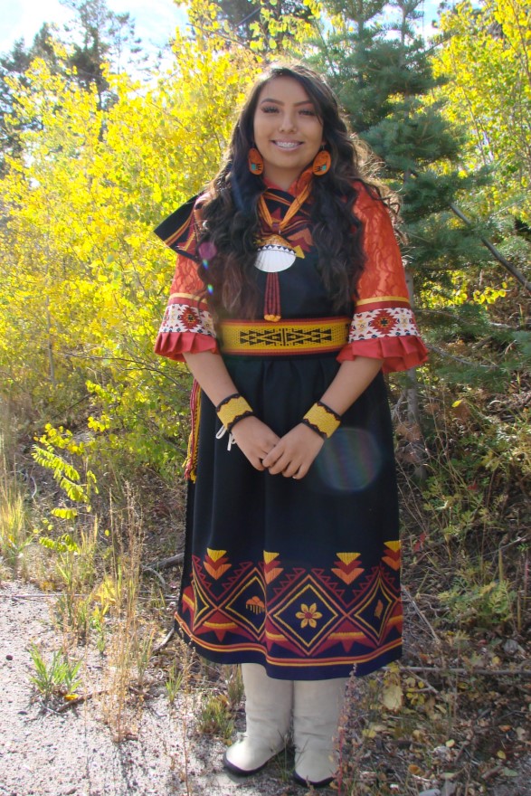 Delilia Gonzales standing and wearing traditional dress of her Pueblo.